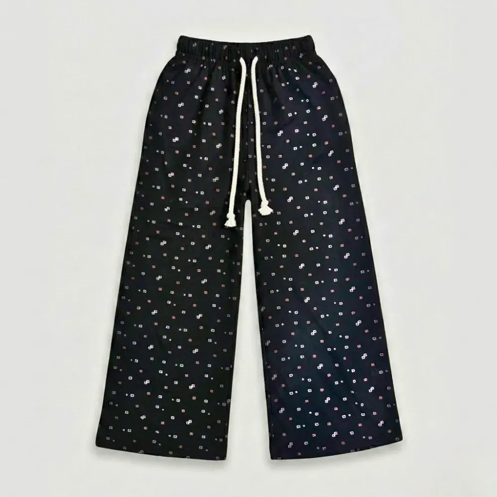 Black pajama pants with small white and pink spots, elastic waistband, and white drawstring.