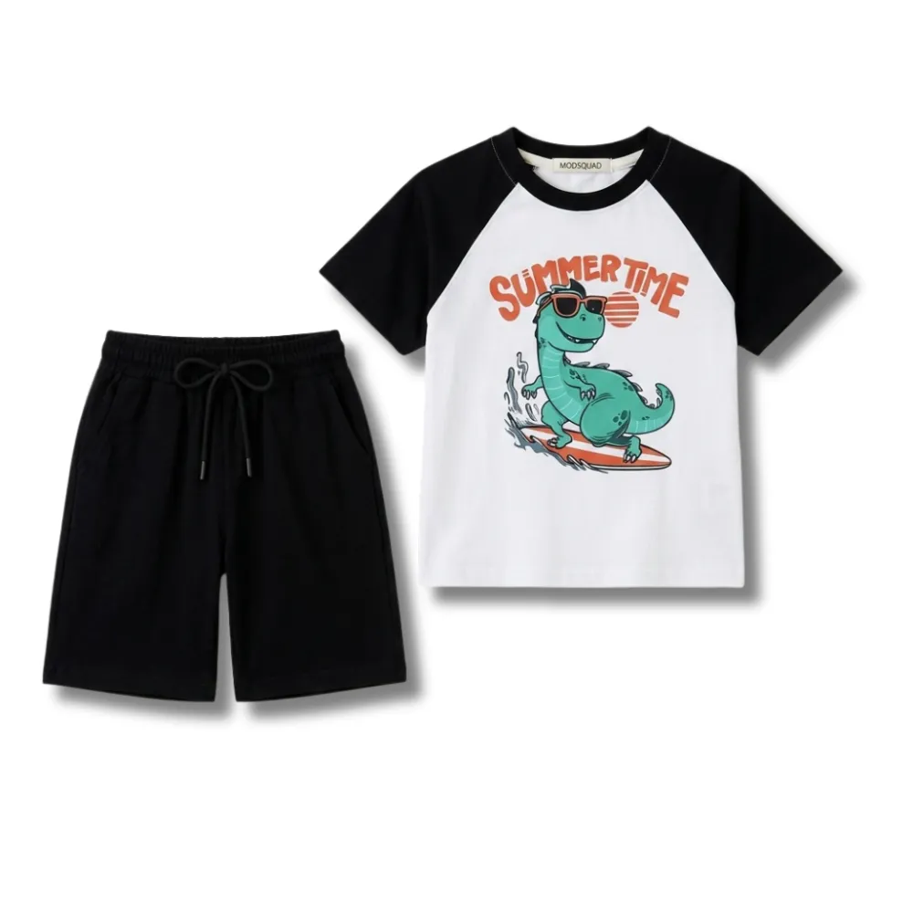 Boys' summer two-piece outfit featuring a white and black raglan t-shirt with a cartoon surfing dinosaur graphic and solid black athletic shorts. The tee features a green dinosaur wearing sunglasses on a surfboard with 'SUMMER TIME' text. The shorts have an elastic waistband and drawstring. Ideal for kids' casual summer wear.