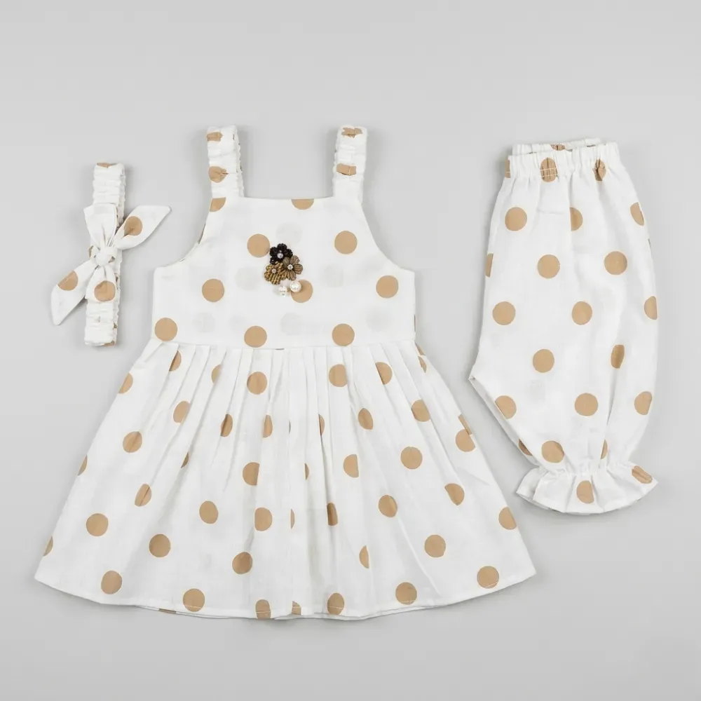 White dress with tan polka dots, matching pants, and hair bow, perfect for a stylish baby girl outfit.