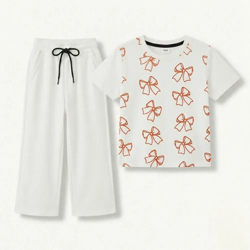 White kids' outfit with orange bow pattern t-shirt and matching white pants with black drawstring.